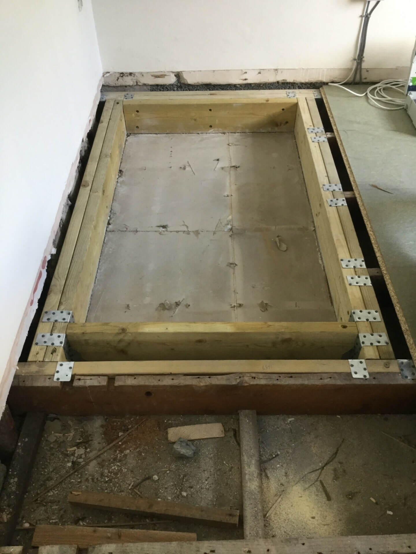 Strengthened floor joists and temporary cover board in place during home lift installation building works, protecting the opening until the lift is fitted.